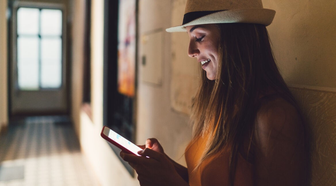 Eine junge Frau findet ihren Weg im Gebäude auf dem Smartphone