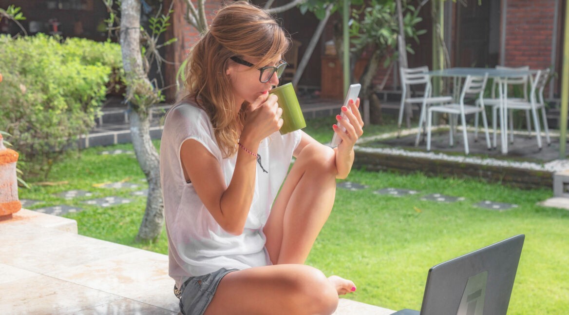 Junge Frau steuert ihren Rasenmäher via App