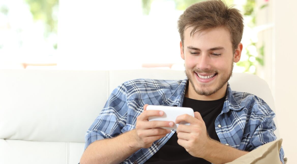 Ein junger Mann spielt auf dem Smartphone Fortnite Battle Royale