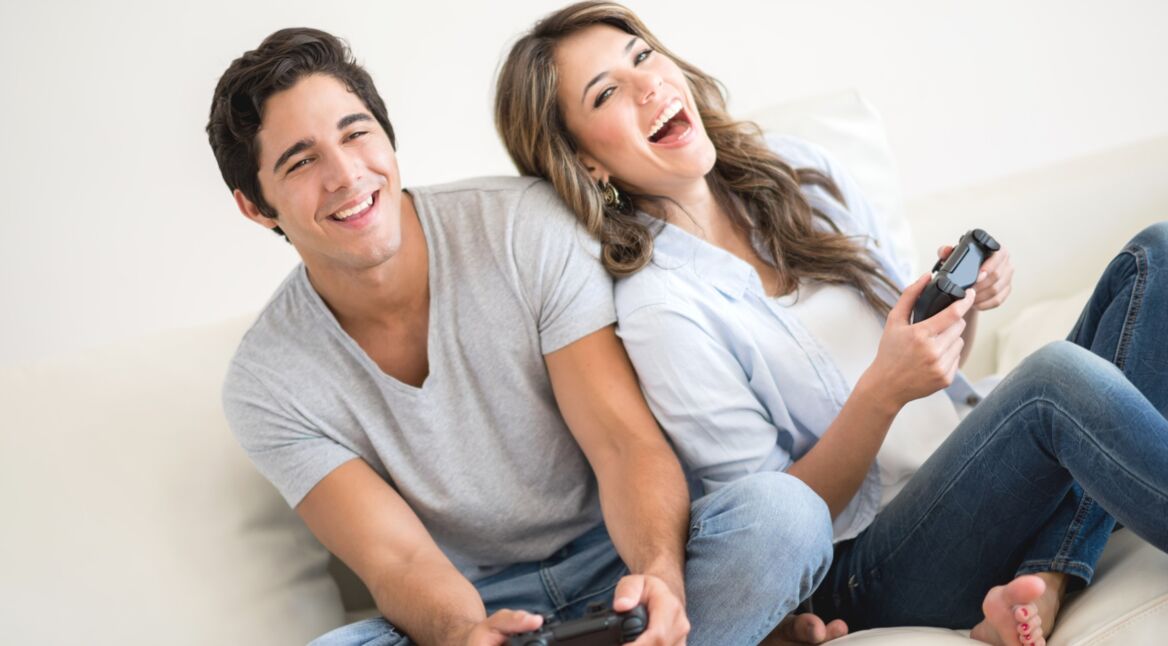 Ein junges Pärchen sitzt auf der Couch und spielt PS4-Spiele