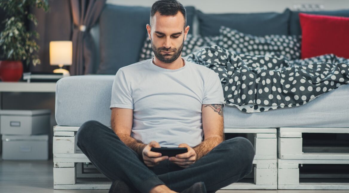 Ein junger Mann spielt auf seinem Smartphone