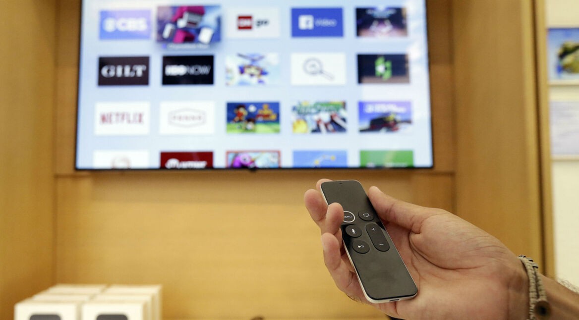 Eine Hand hält die Apple TV Remote.