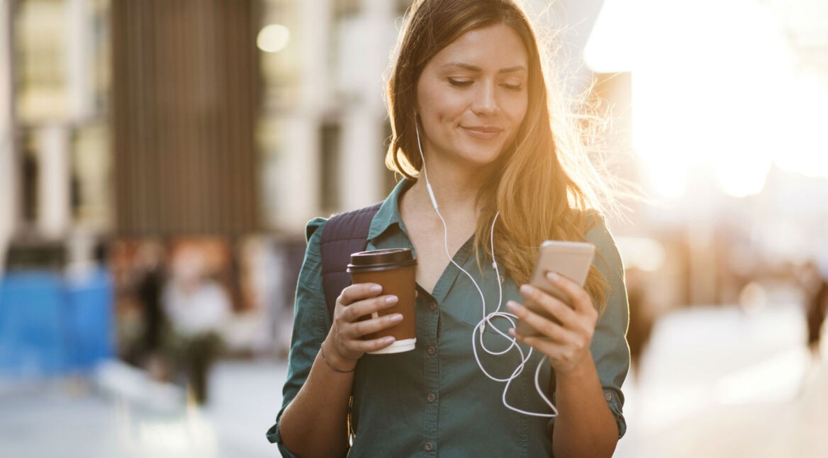 Junge Frau schaut auf ihr Smartphone.