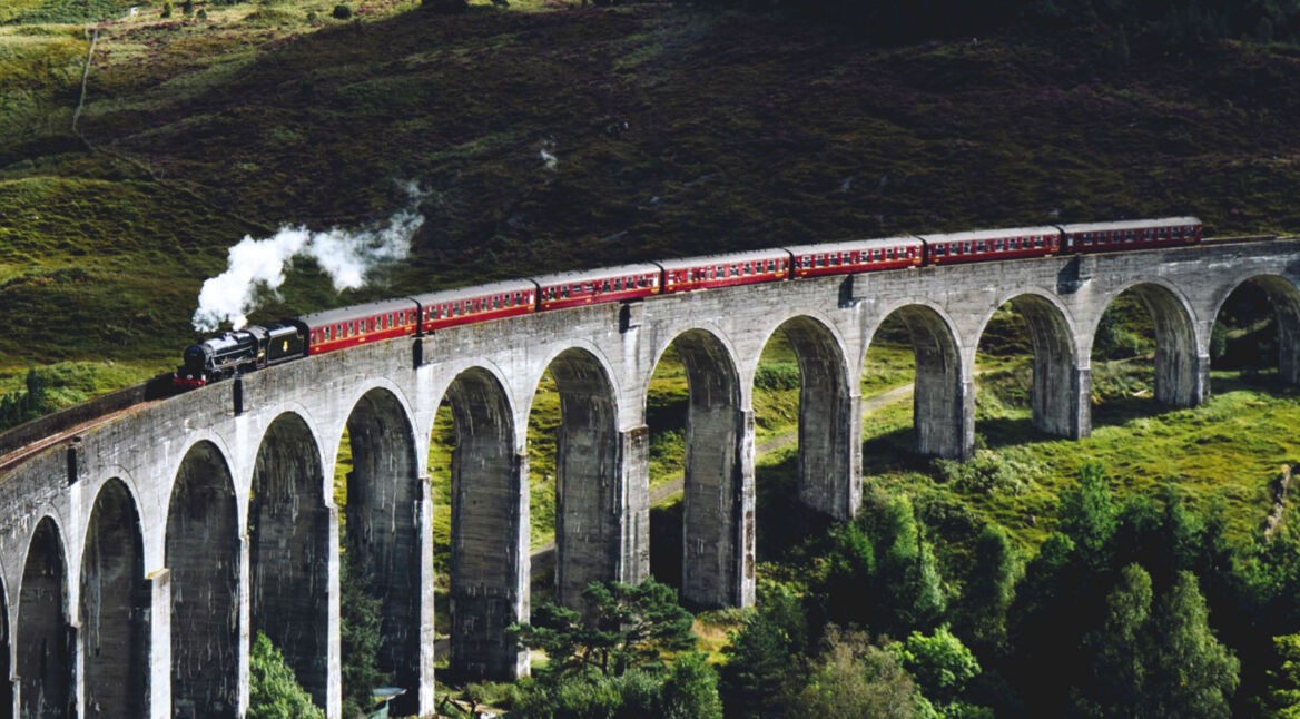 Roter Zug fährt über eine Brücke.