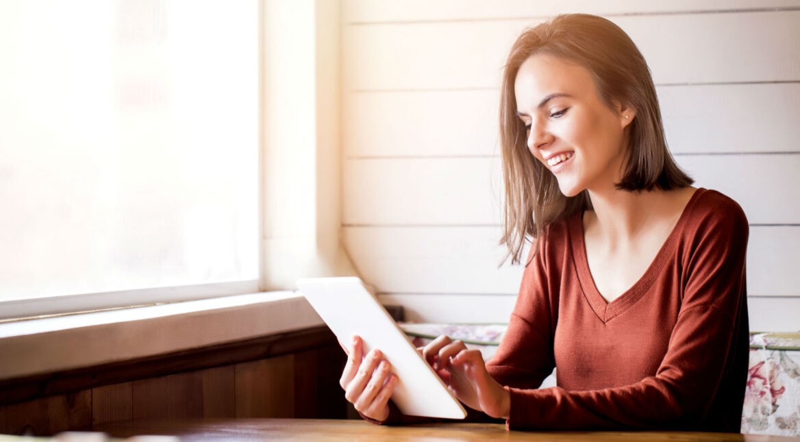 Junge Frau macht Notizen am Tablet.