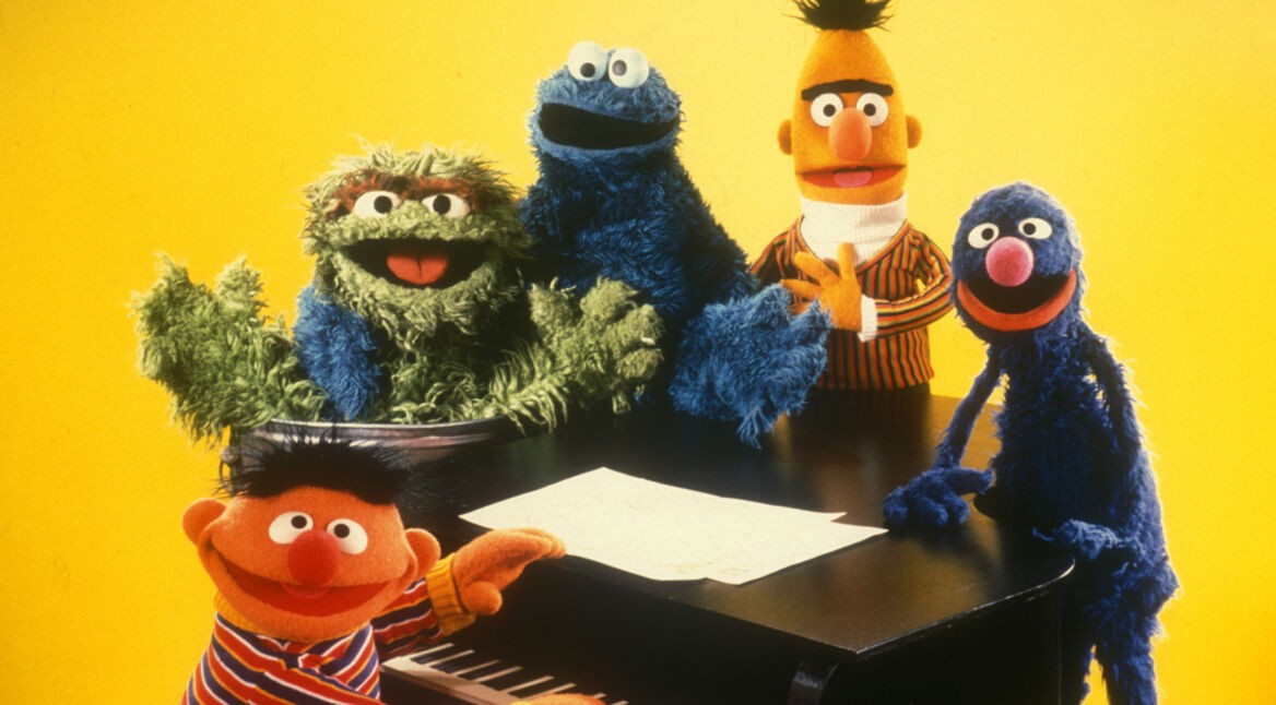 Ernie und Bert mit ihren Freunden an einem Klavier