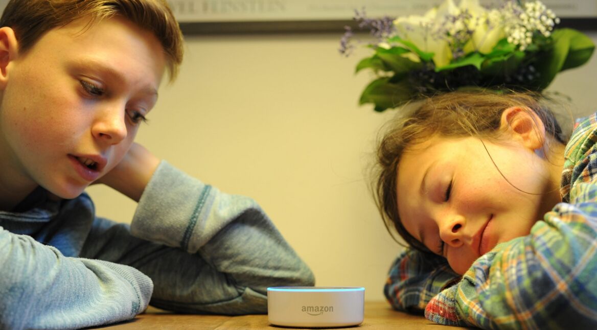 Zwei Kinder hören Alexa zu.