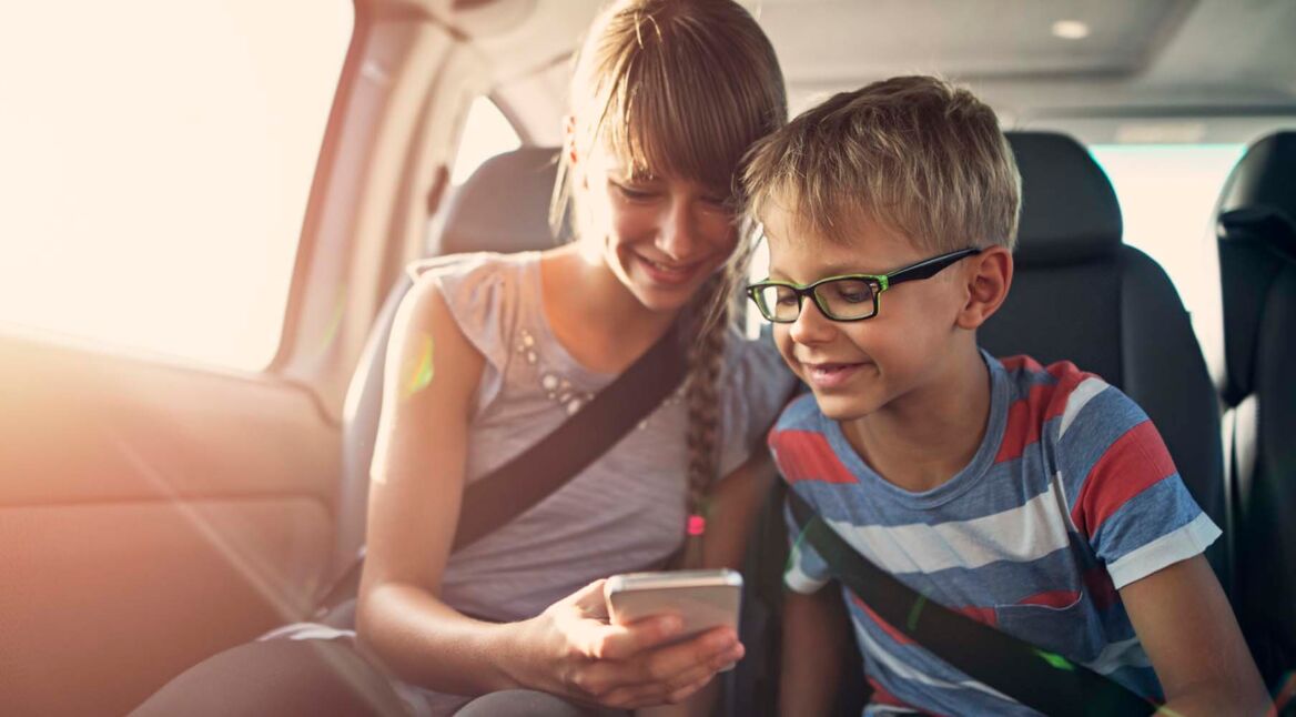 Kids playing smartphone during a road trip