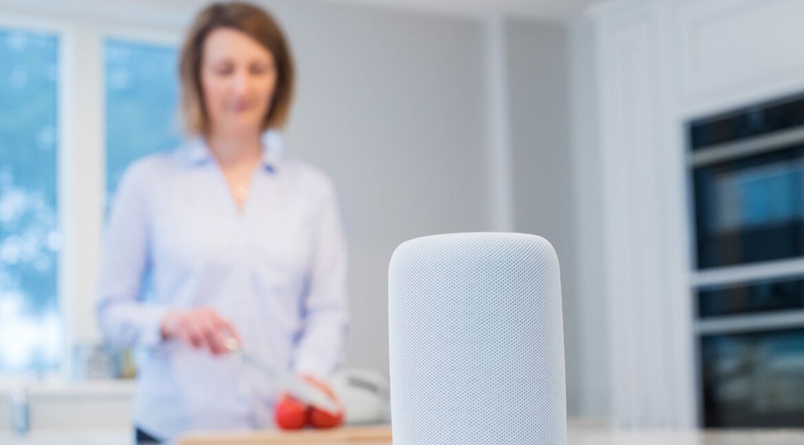 Eine Frau steht in der Küche und telefoniert über ihren HomePod
