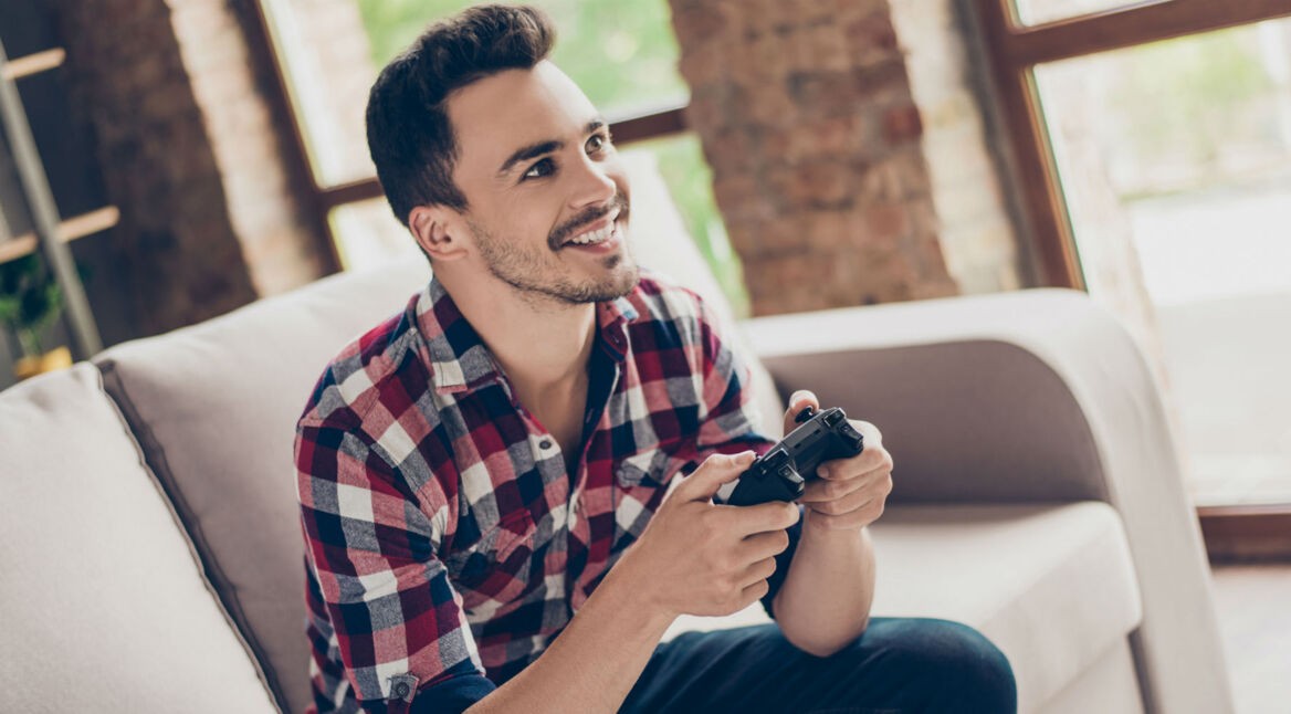 Junger Mann zockt Spider-Man über die Konsole.