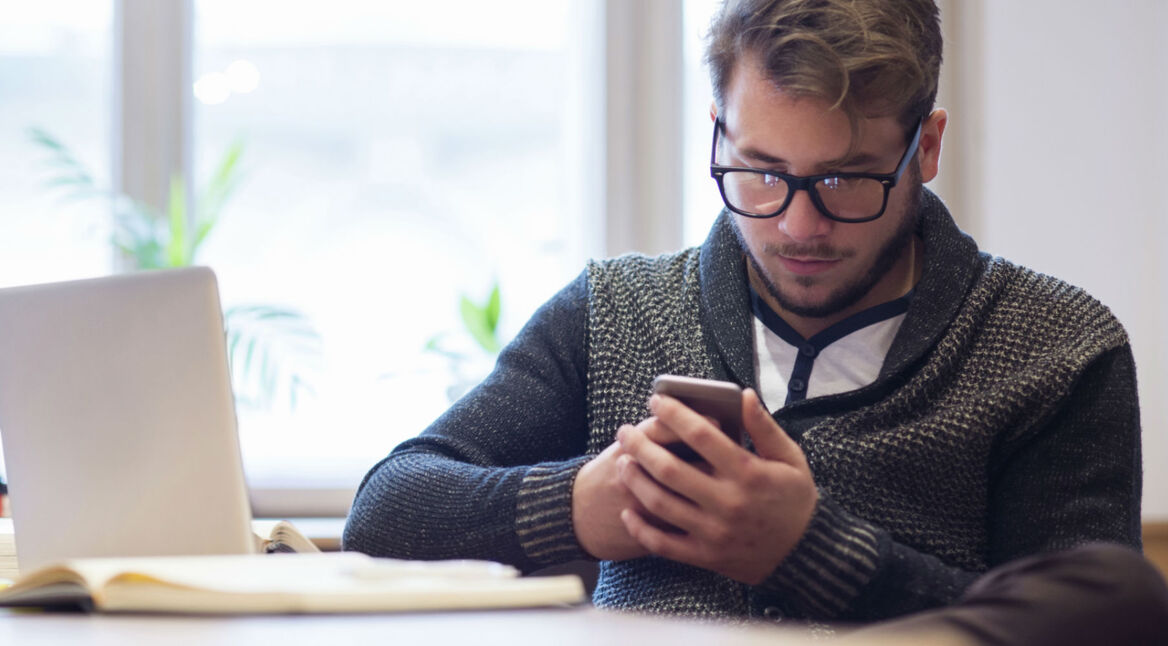 Junger Mann überprüft die Sicherheitseinstellungen seines Smartphones.