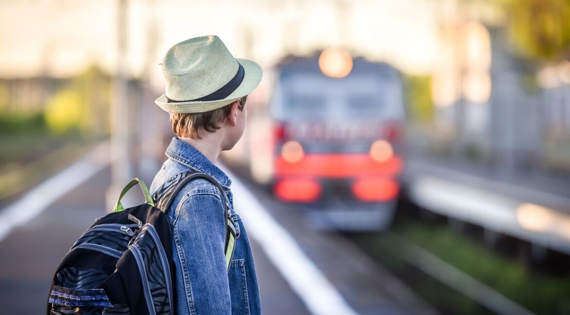 boy with a backpack at the train station waiting for the train