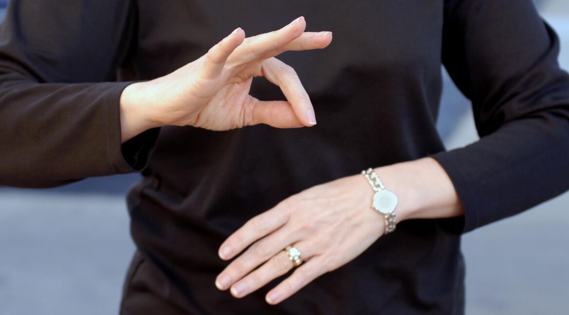 A woman using sign language wearing a black shirt
