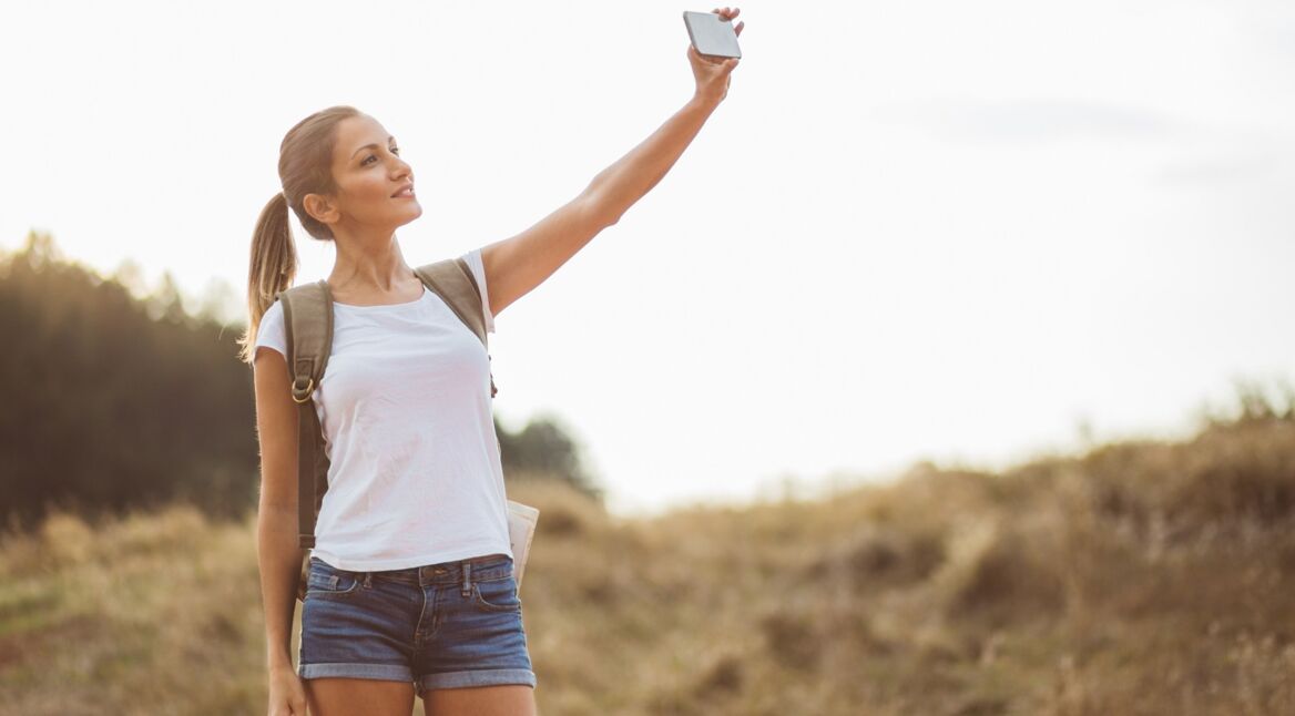 Eine junge Frau macht ein Selfie für ihr neues Facebook Profilbild