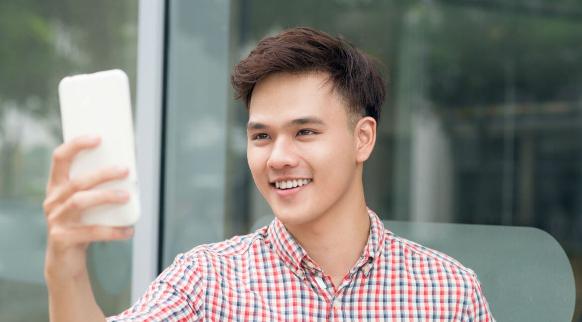 Junger Mann spielt ein AR-Spiel im Facebook Messenger am Smartphone.