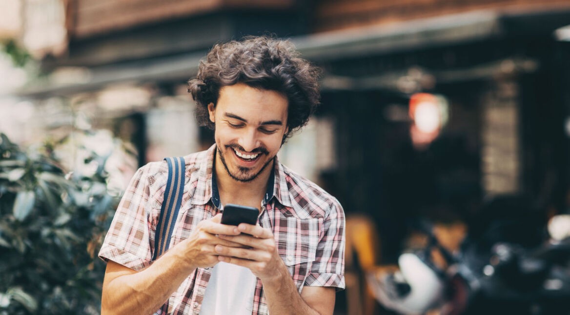 Junger Mann schaut sich YouTube-Stories am Smartphone an.