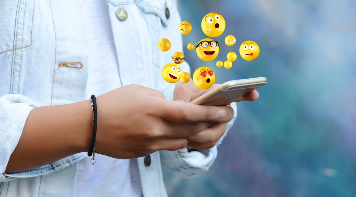 Woman using smartphone sending emojis.