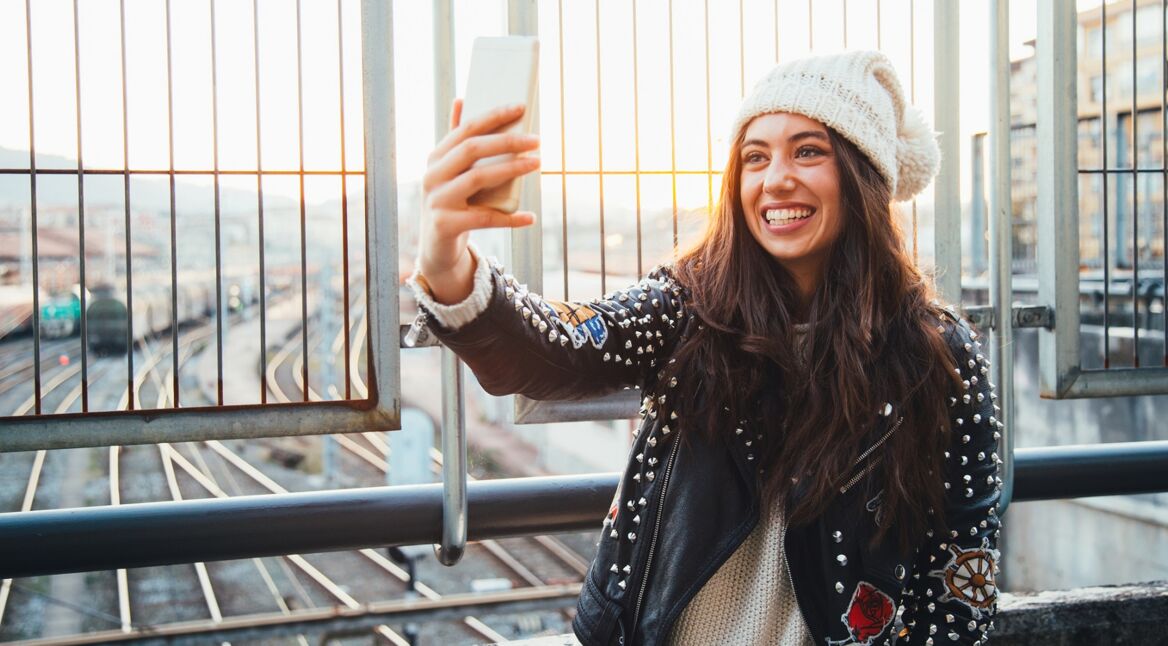 Junge Frau knipst Selfie über einer Eisenbahnbrücke