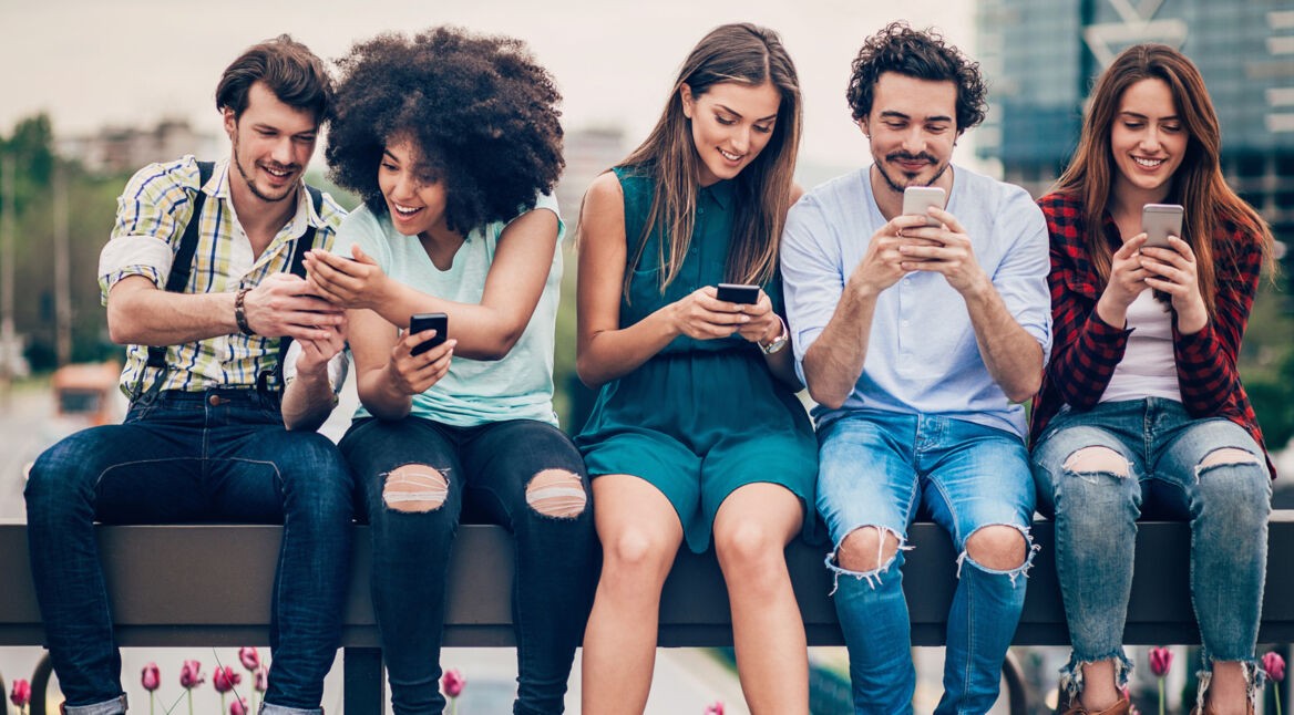 Junge Leute sitzen auf einer Mauer und installieren Android P