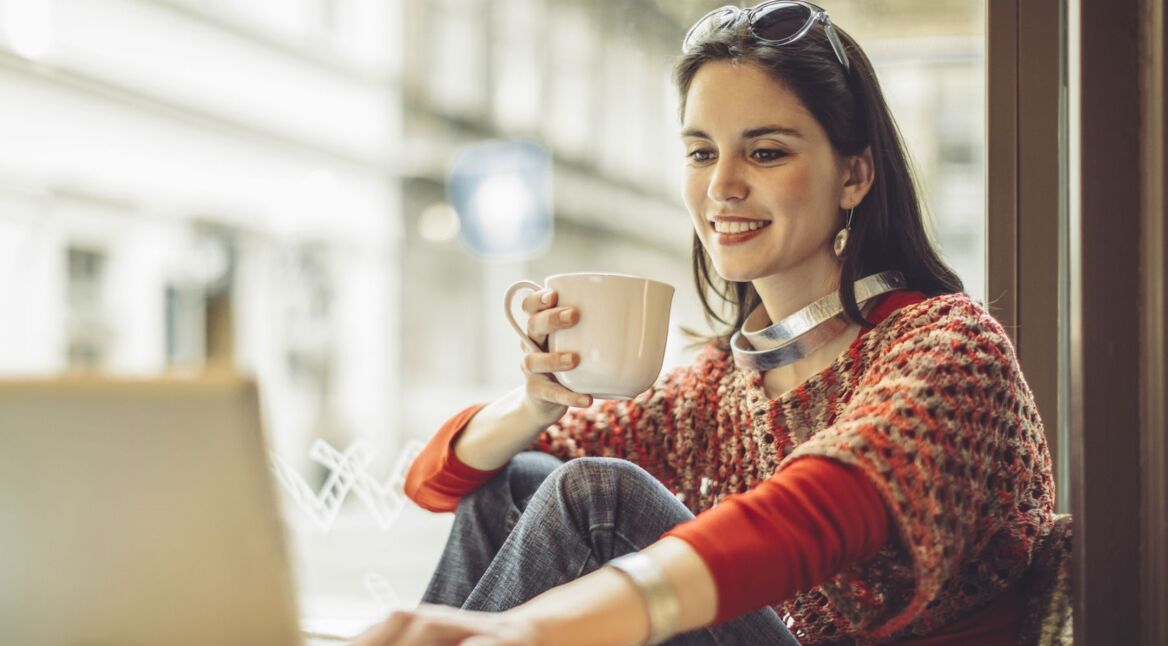 Eine junge Frau sitzt am Fenster und verändert ihre Gmail-Oberfläche