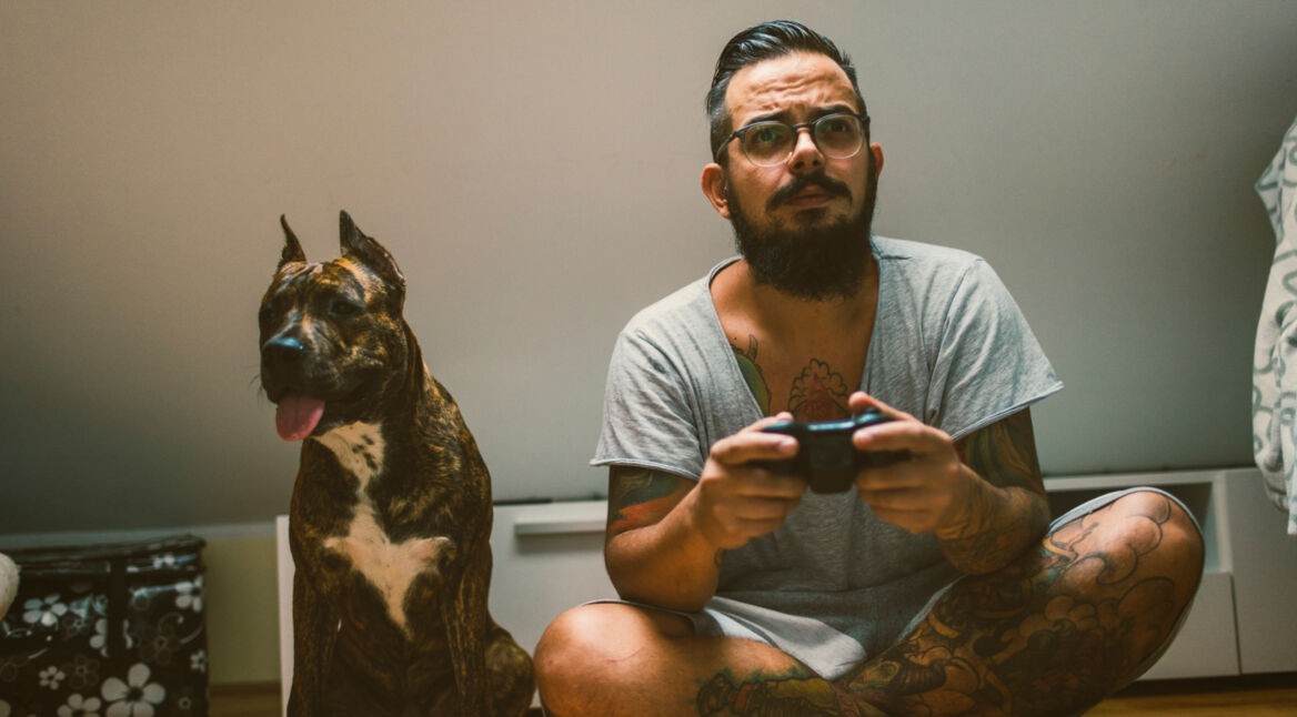 Mann mit Hund beim Zocken