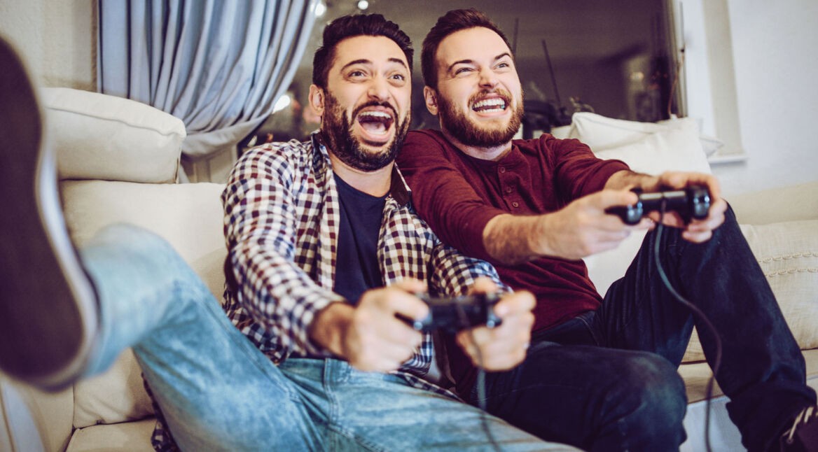 Zwei Männer zocken auf dem Sofa PS4