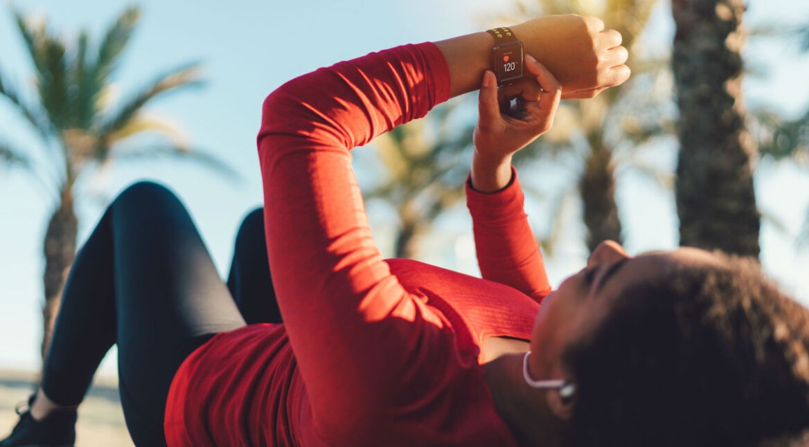 Junge Frau nutzt Fitness-Tracker beim Sport.