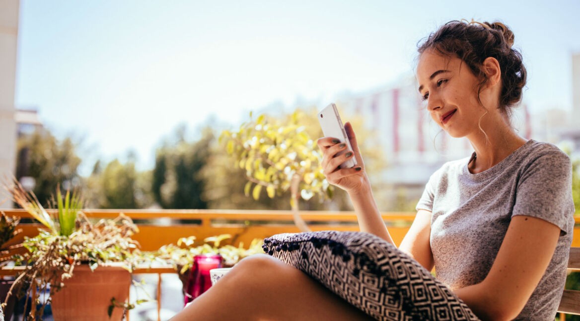 Junge Frau spielt am Smartphone ein entspannendes Spiel.