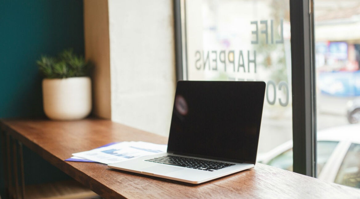 Laptop liegt aufgeklappt mit schwarzem Bildschirm auf dem Tisch.