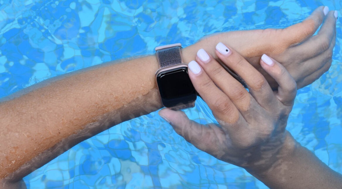 Eine Apple Watch am Arm einer Person, über der Wasseroberfläche eines Pools