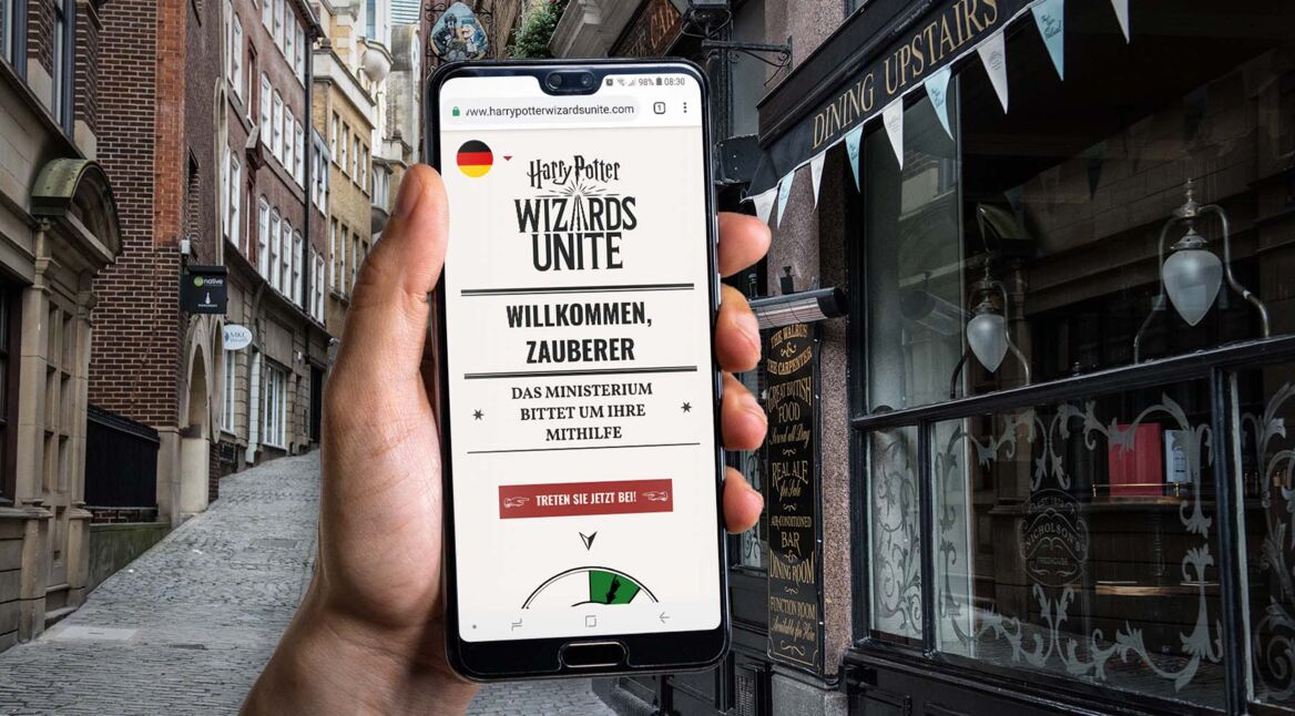 Hand hält ein Smartphone mit einem Screenshot der Webseite von Harry Potter: Wizards Unite.