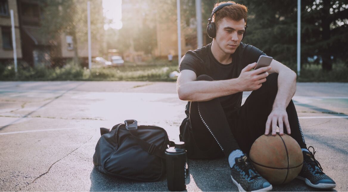 Junger Mann hört nach dem Basketball spielen einen NBA-Podcast