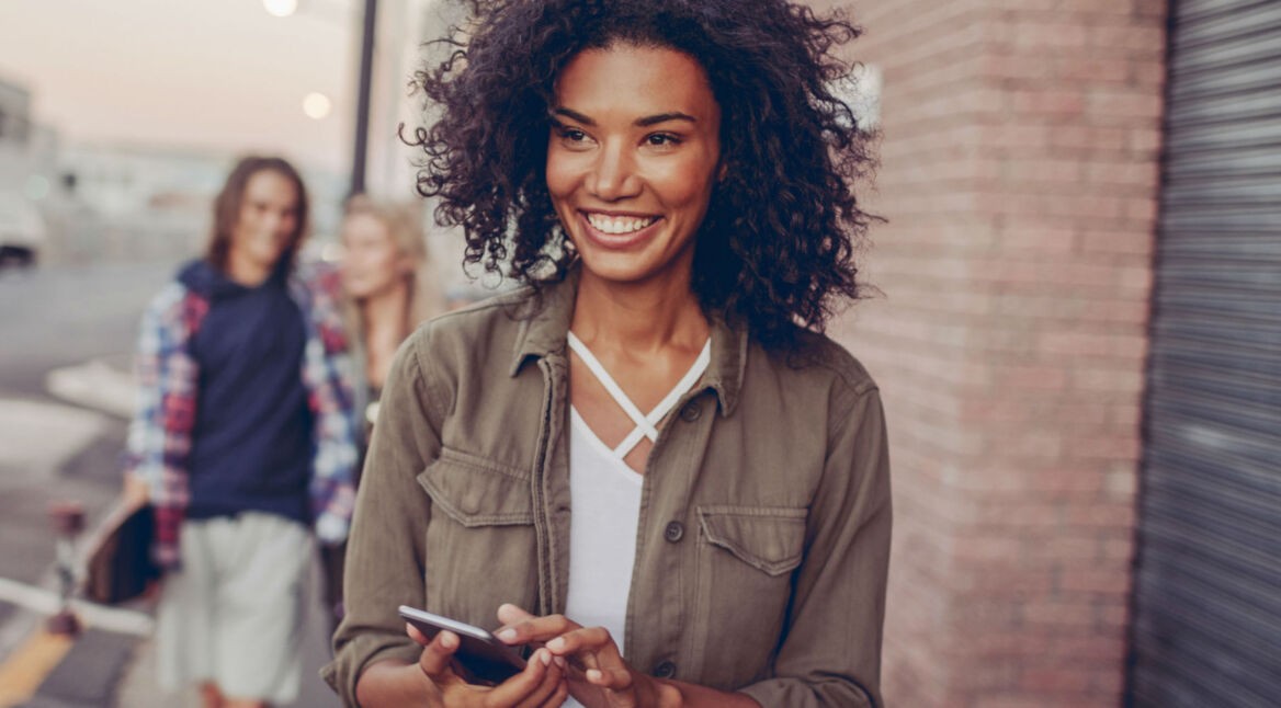 Junge Frau lächelt und macht einen Screenshot mit ihrem Smartphone.