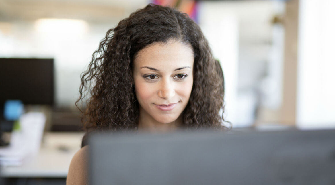 Junge Frau löst das Problem mit ihrem PC-Bildschirm und arbeitet weiter.