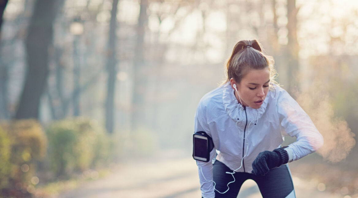 Junge Frau steuert beim Laufen ihre Musik über die Apple Watch.