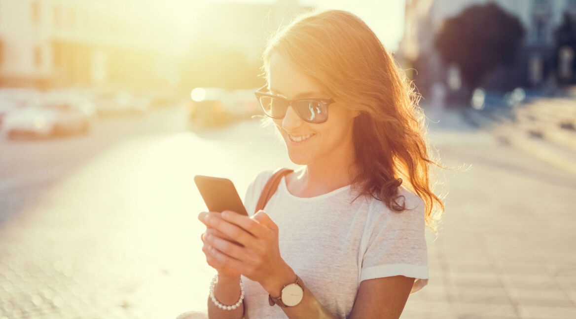 Junge Frau testet Android-9-Funktionen an ihrem Smartphone.