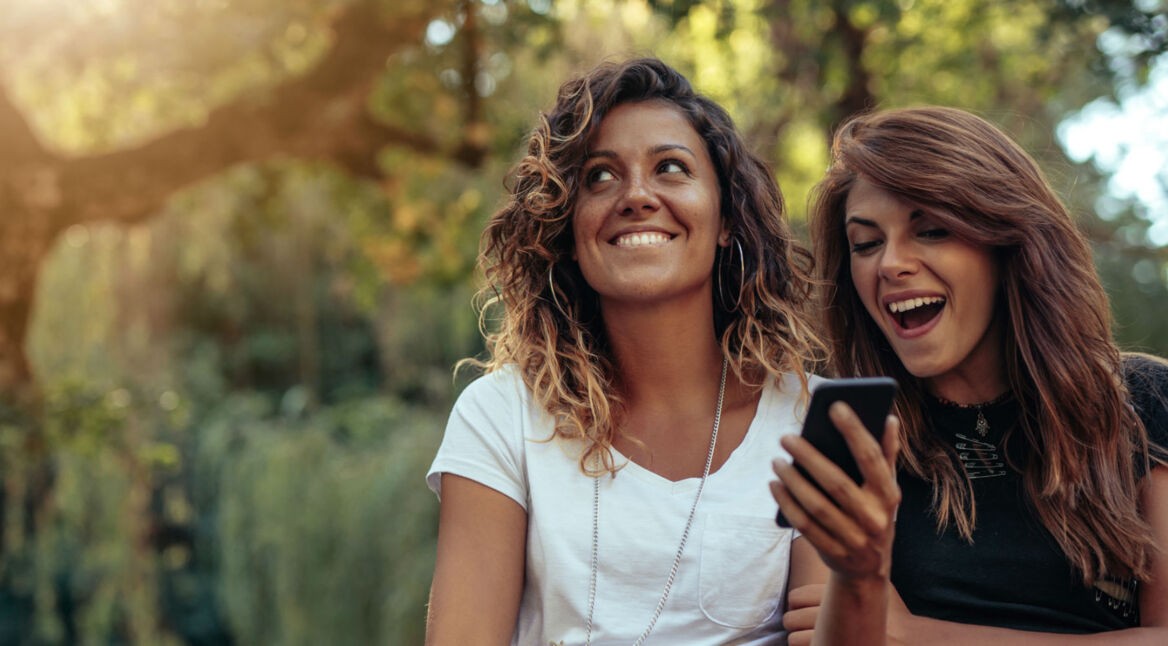 Freundinnen korrigieren am Smartphone die Gesichtserkennung der Fotos-App.