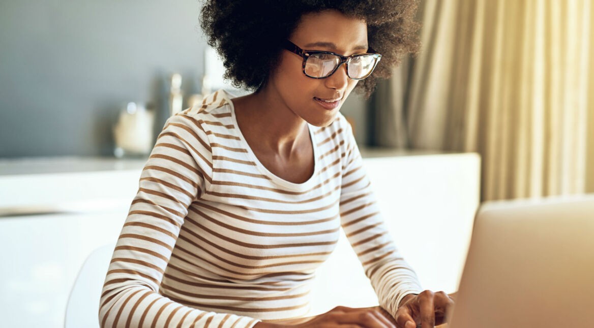 Junge Frau nutzt Alexa am Laptop.