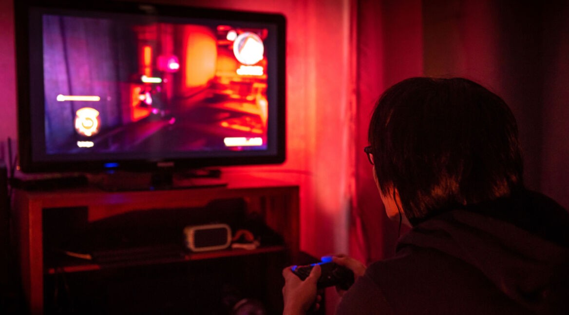 Junger Gamer sitzt vor einem großen Bildschirm