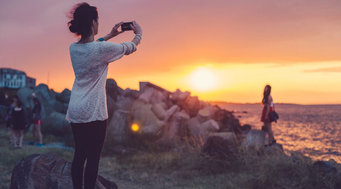 Eine Frau schießt ein Foto vom Sonnenuntergang