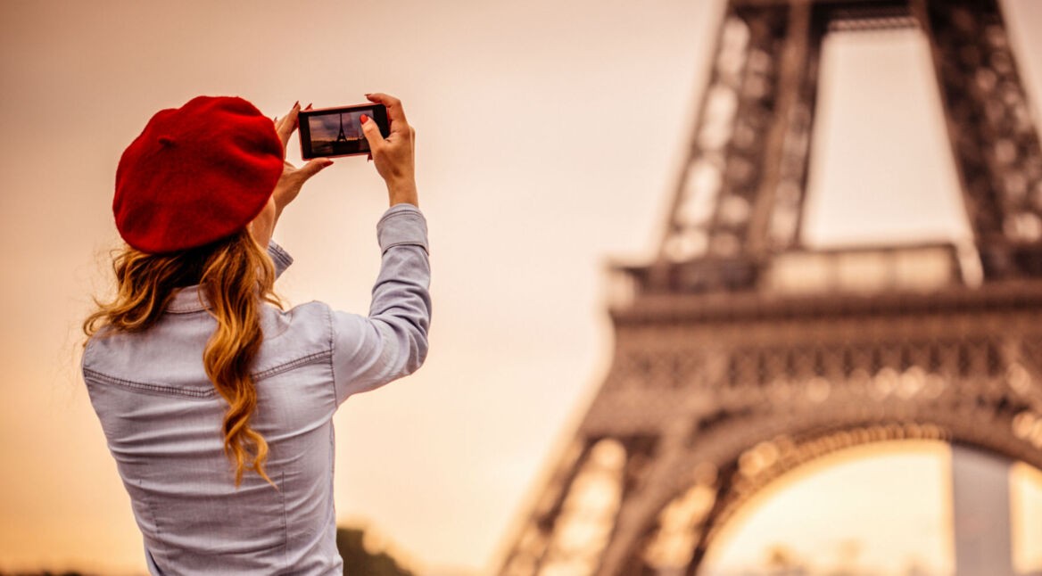 Junge Frau nimmt am Smartphone RAW-Fotos vom Eiffelturm auf.