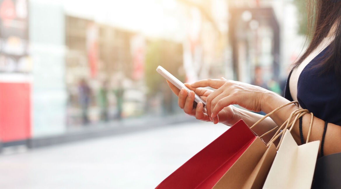 Frau sieht am Smartphone ihre Google-Käufe ein.