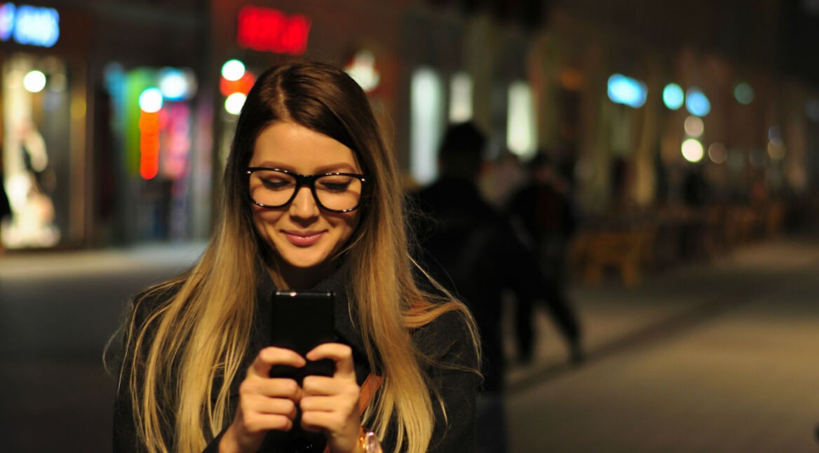 Junge Frau aktiviert am Smartphone den Dark Mode ihrer Android-App.