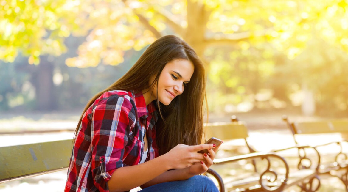 Junge Frau teilt eine Netflix-Serie am Smartphone mit Freunden.