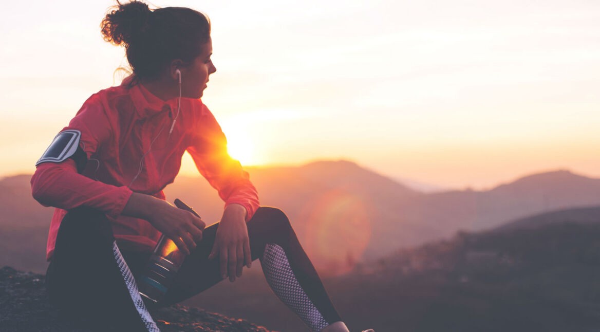 Frau macht Sport und zeichnet mit ihrem Smartphone auf, das sie am Arm trägt.