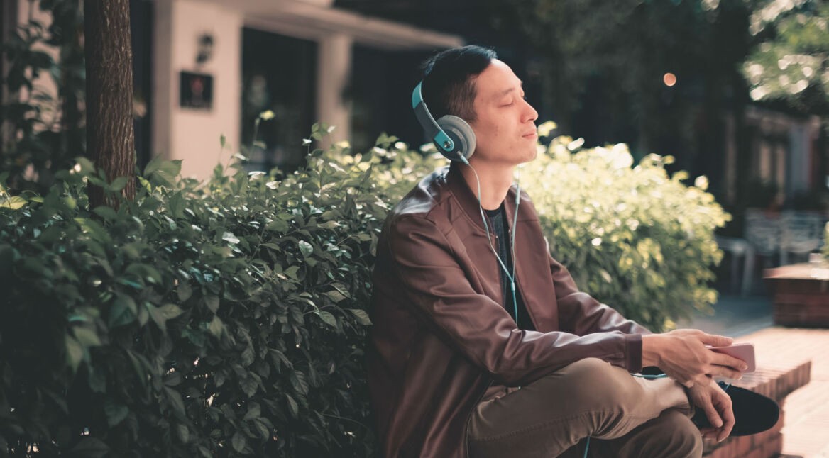 Junger Mann hört sich Apple-Music-Inhalte mit dem Smartphone an.