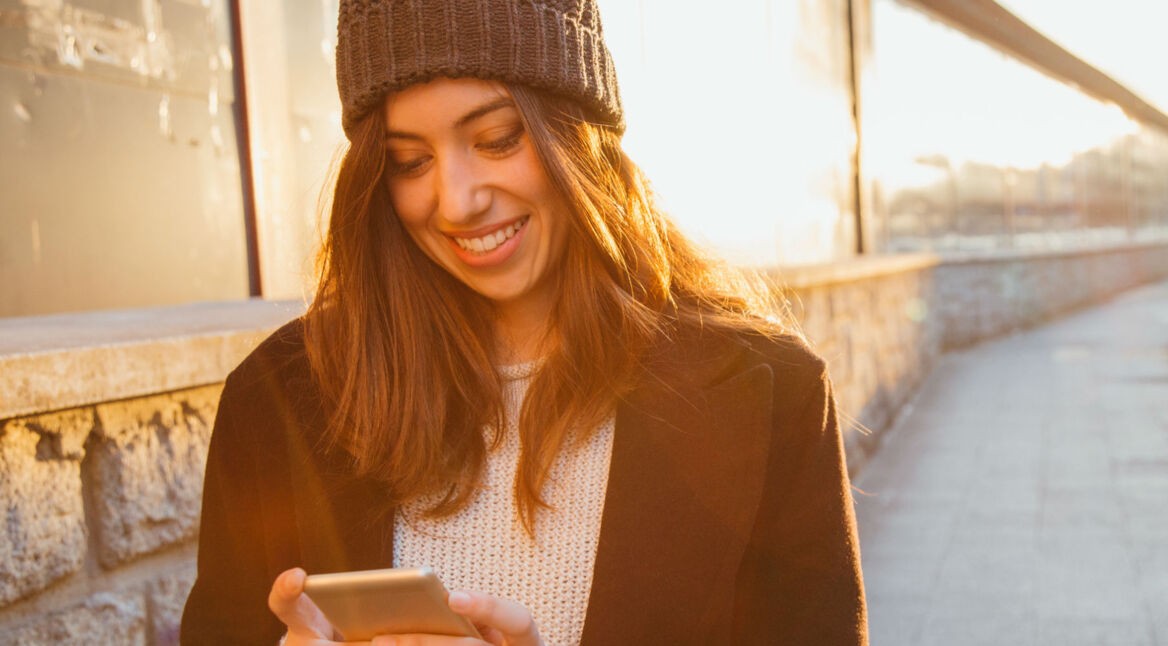 Junge Frau surft am Smartphone mit Safari.