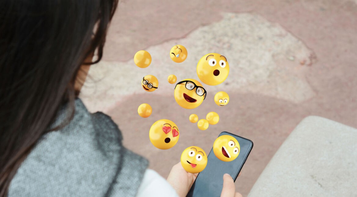 Junge Frau nutzt Emojis auf ihrem Smartphone.