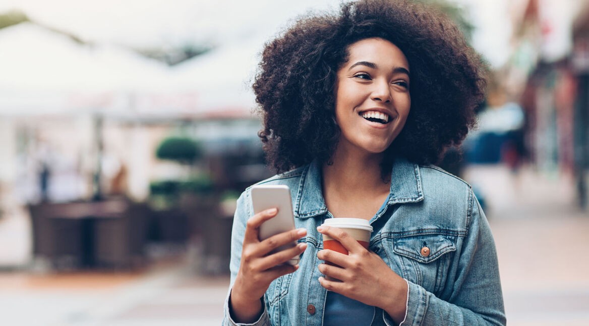 Black girl with phone and coffee outdoors in the city