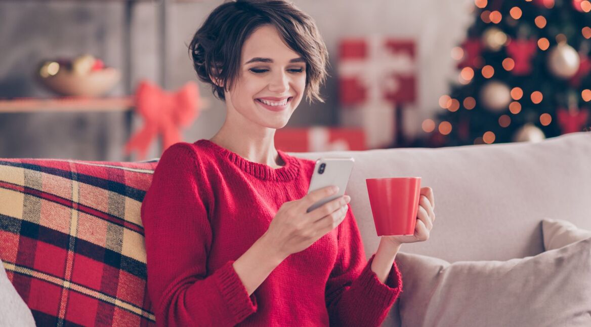 Frau schaut lächelnd auf ihr Handy.